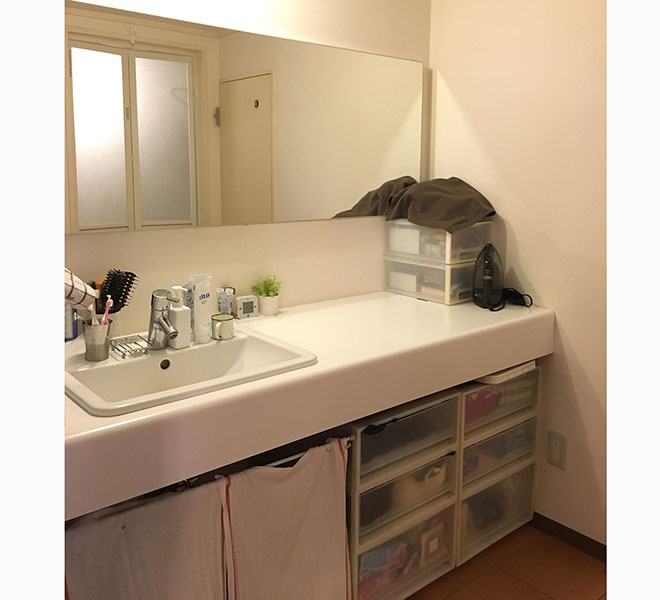 洗面所はコストを抑えるため、シンプルな天板の上に洗面ボウルを設置してもらうだけにとどめた。下部はオープンにして既製品のボックスなどで収納。大きな鏡はNさん自身が購入して取り付けている。