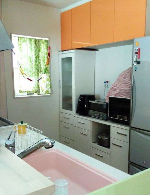 キッチンは側面をグリーン、吊り戸棚をオレンジにして、その場にいるだけで楽しくなる空間に。手前のカウンターは、お皿の一時置きとして活用している。