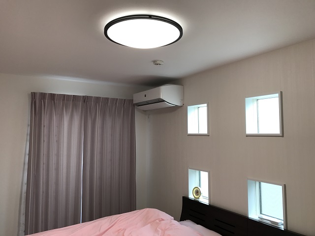 シンプルな寝室はシングルベッドを2つ並べて利用。奥から、紫色のカーテン、ピンクとベージュのシーツ、白の壁とグラデーションになるように考えている。